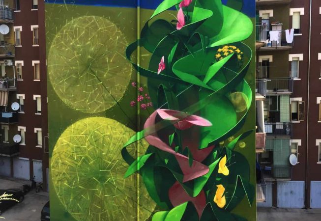 Big wall painting on building with green leaves and pink flowers. Total building view. Aerosol art by Dado