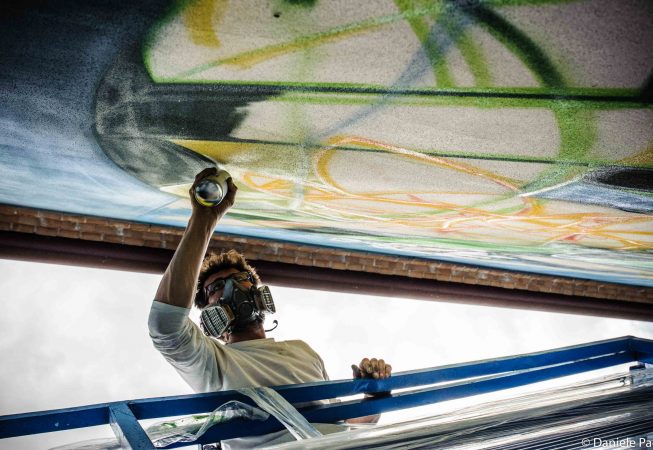 Closeup detail of Dado painting a Graffiti-mural lettering - bottom view of the artist painting with a spray can