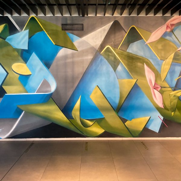 Detail of a wall decoration representing intersecting blue ,green and gray ribbons in a sophisticated geometrical pattern. Aerosol art by Dado.