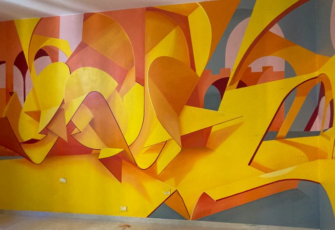 Total view of an interior wall decoration representing an abstraction of Bologna's arcs, Portici in yellow-orange tones. Artwork by Dado.