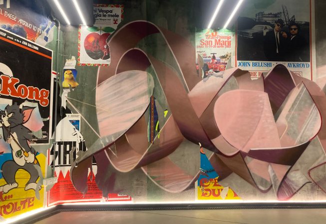 Detail of a decorated garage wall recreating a street underground ambient with spray can lettering artworks and torn paper posters. Artwork by Dado.