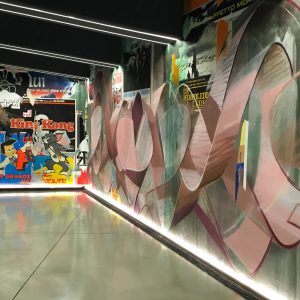 Right total view of a decorated garage wall recreating a street underground atmosphere with spray can lettering artworks and torn paper posters. Artwork by Dado.