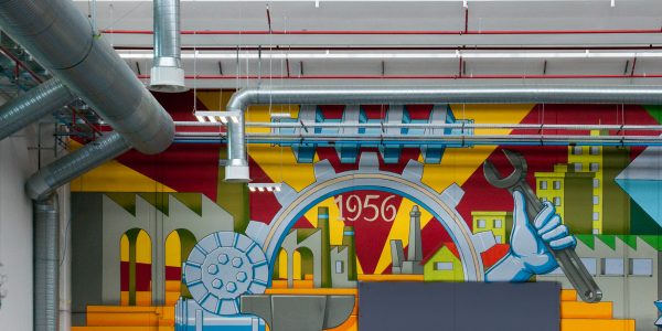 Detail of a big wall painting representing the company first logo in the factory warehouse interior. Wall painting by Dado.