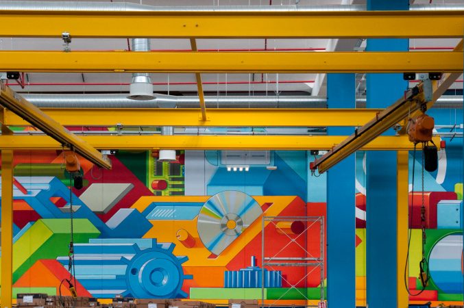 Detail of a big wall painting inside a factory warehouse representing the evolution of the company in the digital era. Wall painting by Dado.