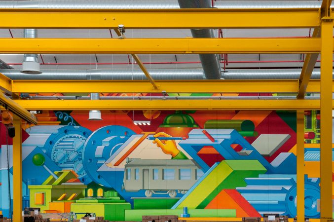 Detail of a big wall painting inside a factory warehouse representing the evolution of the company in the industrial era. Wall painting by Dado.