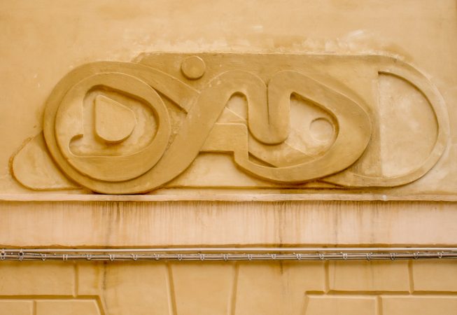 Bas-relief sculpture in a contemporary graffiti lettering fixed on a above a Medieval vault architecture well pairing. Front view detail. Artwork by Dado