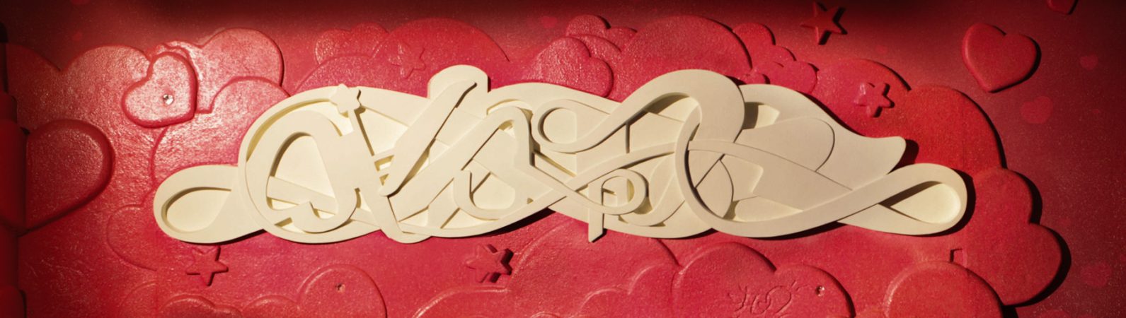 Bas-relief sculpture in a contemporary graffiti lettering plain white on pink hearted background. Front wide view Artwork by Dado
