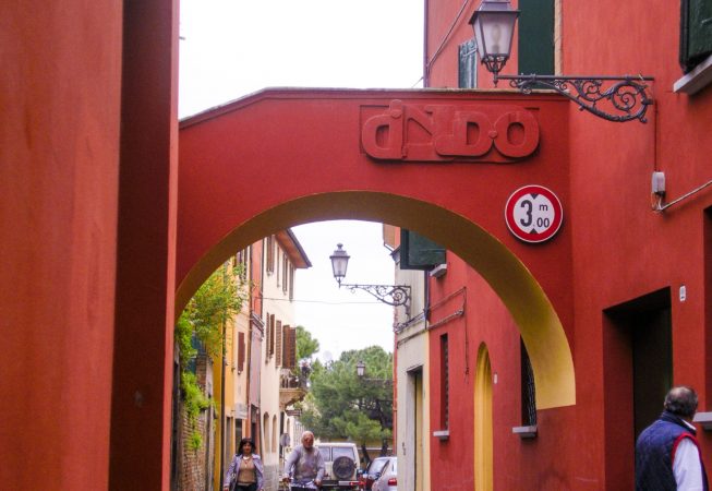 Bas-relief sculpture in a contemporary graffiti lettering fixed on a above a Medieval bridge red architecture. Front view Artwork by Dado