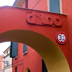 Bas-relief sculpture in a contemporary graffiti lettering fixed on a above a Medieval bridge red architecture. Front view Artwork by Dado