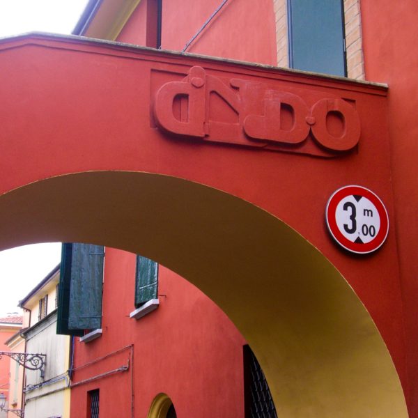 Bas-relief sculpture in a contemporary graffiti lettering fixed on a above a Medieval bridge red architecture. Front view Artwork by Dado