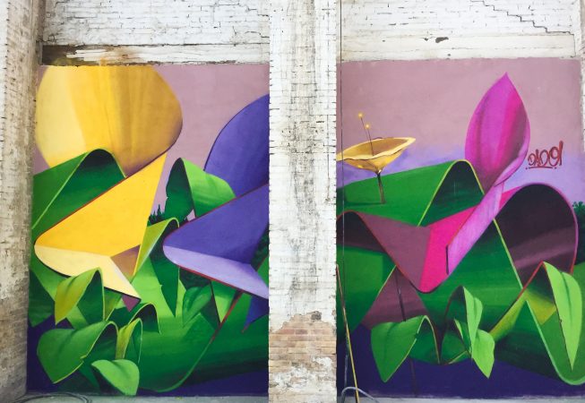 A triptych mural painting of flowers in three different colors on a white bricks wall in a wide open space, double flower view. Artwork by Dado