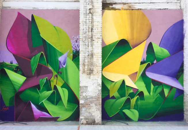 A triptych mural painting of flowers in three different colors on a white bricks wall in a wide open space, double flower view. Artwork by Dado