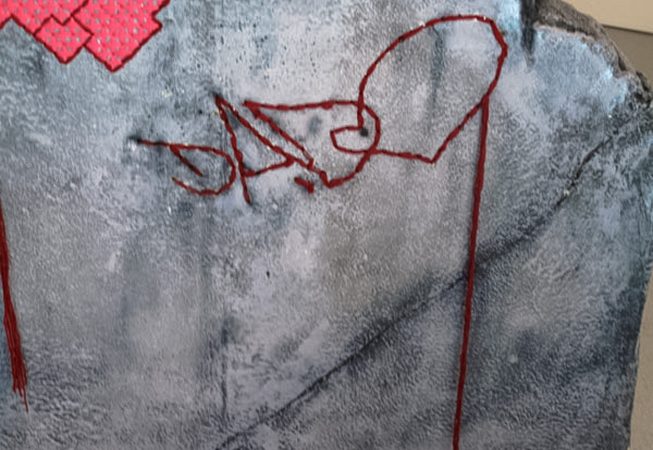 A closeup detail of Dado's tag stitched on a rock sculpture.
