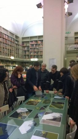 People inside an art gallery observing artistic sketches over a glass desk