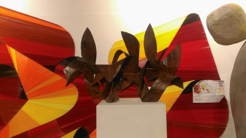A copper sculpture in front a wool made graffiti inside a gallery. Artworks by Dado