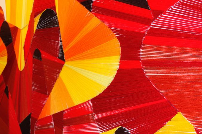 A closeup detail of a wool made graffiti in the tones of yellow, orange and various reds. Artworks by Dado