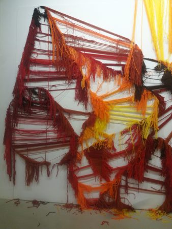 A closeup detail of the skeleton of a wool made graffiti in the tones of yellow, orange and various reds, after being ripped. Artworks by Dado
