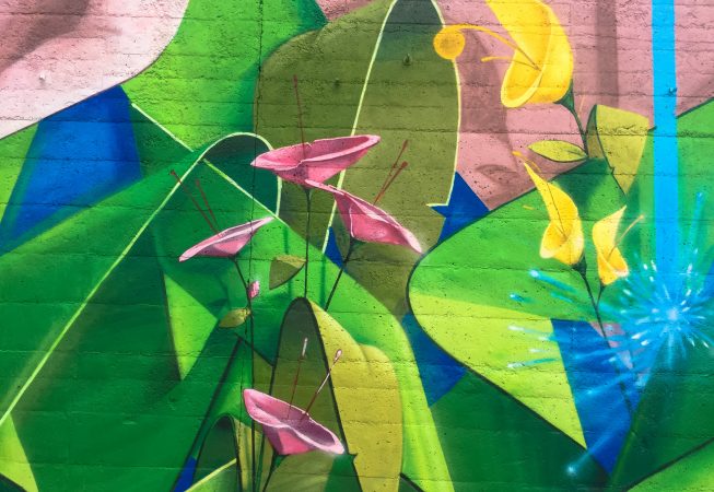 Detail of yellow and pink flowers on a Mural Painting depicting the name of the city Covignano woven with colored flowers and green leaves. Artwork by Dado