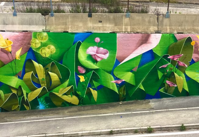 Central part of a Mural Painting depicting the name of the city Covignano woven with colored flowers and green leaves. Artwork by Dado