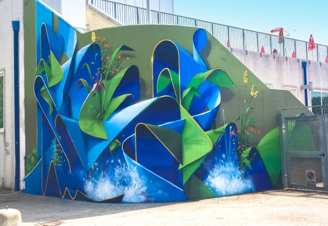 Total view of a large mural painting depicting wide sinuous blue ribbons decorated with purple, red and yellow flowers and green leaves and water splashes. Artwork by Dado