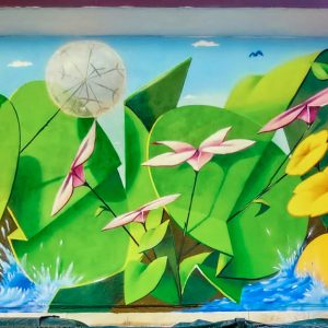 Total view of a large mural painting depicting big green leaves with geometric rounded shapes, composing the tag Dado, and big yellow-orange flowers along with smaller pink and light yellow flowers floating on deep blue water. Artwork by Dado