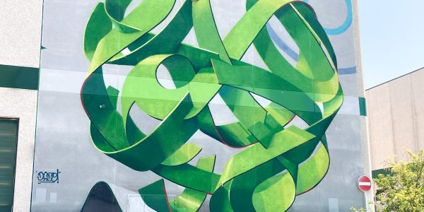 Total view of a mural painting depicting a spherical wildstyle graffiti forming the tag Dado in green tones.