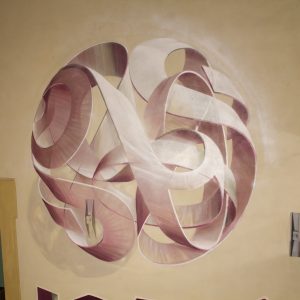 Mural painting inside a depicting a spherical wildstyle graffiti forming the tag Dado colored in a vanishing light pink and winy tones.