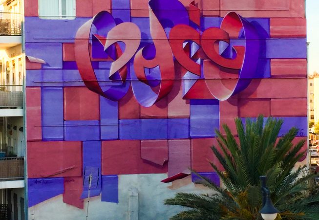 Mural painting on an high building face depicting floating bent ribbons creating two names altogether the tag Dado and the name Eva in a pale red and electric blue tones