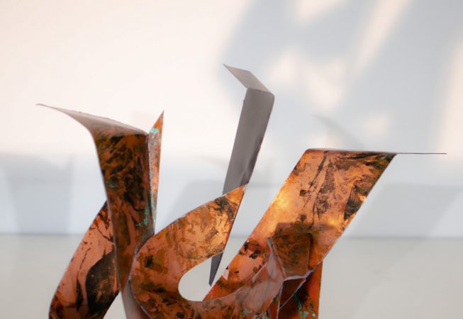 Front view of a sculpture made of copper ribbons forming M and G letters. Artwork by Dado