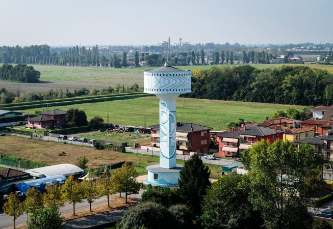 Vista totale da lontano della torre del grande serbatoio idrico di Mira, provincia di Venezia, sul quale è dipinto l'Orologio Solare senza Gnomone dell'artista Dado. La grande torre si staglia sul panorama della campagna di Mira.