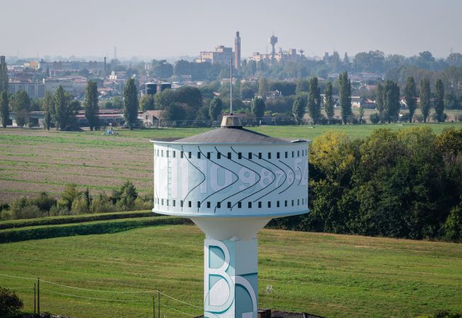 Vista dalontano della parte superiore, dall'alto, della del grande serbatoio idrico di Mira, provincia di Venezia, sul quale è dipinto l'Orologio Solare senza Gnomone dell'artista Dado. Sullo sfondo la vista panoramica sulla campagna di Mira, Venezia.